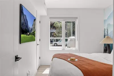 a white bedroom with a bed and a window at Newly Built 2BR Mountain Escape in DT Canmore! in Canmore