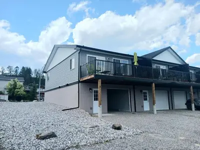 a house with a balcony on a gravel driveway at 3 Bed Townhouse, Mountain Views, Large Deck, Air Con, Garage in Invermere