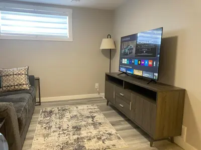 a living room with a flat screen tv on a wooden cabinet at Private one Bedroom Suite for Rent in Calgary