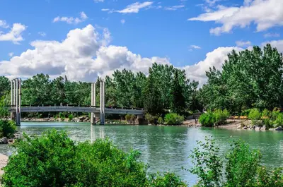 a bridge over a river with trees in the background at Basement Suite in Calgary - Short Drive to Banff in Calgary