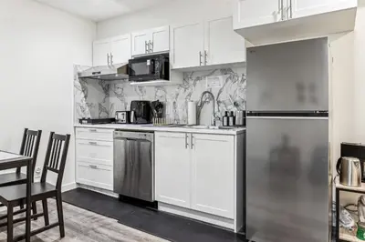 a kitchen with white cabinets and a stainless steel refrigerator at Basement Suite in Calgary - Short Drive to Banff in Calgary