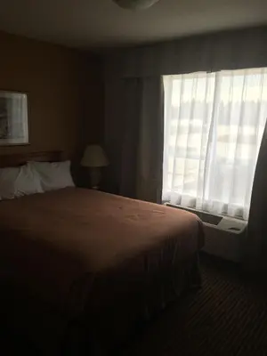 a hotel room with a bed and a window at Foxwood Inn and Suites in Fox Creek