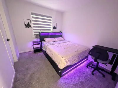 a bedroom with a bed and a desk and purple lighting at Edith Gate Luxe Bedroom 2 Homestay in Calgary