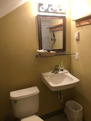 a bathroom with a toilet and a sink and a mirror at Crowsnest Vineyards Guesthouse in Keremeos