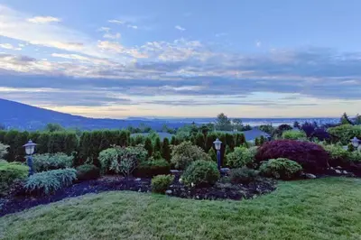 a garden with flowers and trees on a hill at Stunning view in elegant 1 bedroom suite in West Vancouver