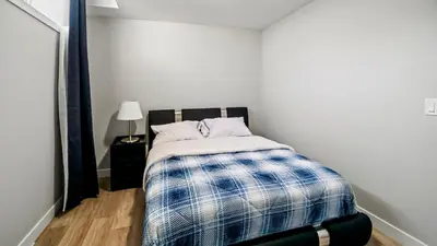 a bedroom with a bed with a blue and white blanket at Serene Stays in Calgary
