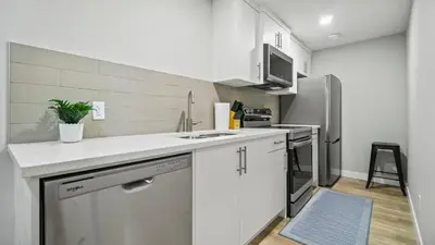 a white kitchen with a sink and a refrigerator at Serene Stays in Calgary