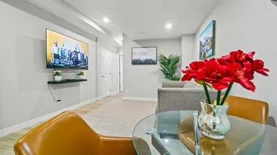 a living room with a glass table with red flowers on it at Serene Stays in Calgary