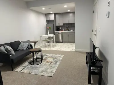 a living room with a couch and a kitchen at Modern & Stylish Private Suite in Pine Creek in Calgary