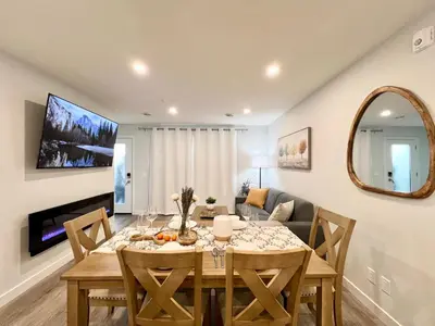 a dining room with a table and a couch at Mountain View New Luxury Condo at Banff Entrance in Canmore