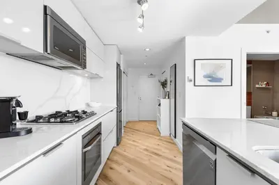 a white kitchen with a sink and a stove at Luxury Central Apartment with City Views in Vancouver