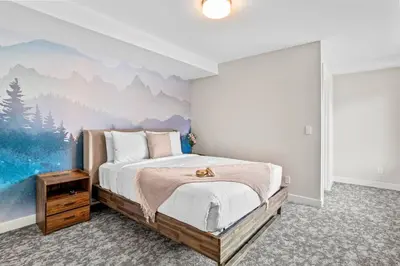 a bedroom with a bed with a painting on the wall at Charming 2BR Haven in Canmore Near DT and Banff in Canmore