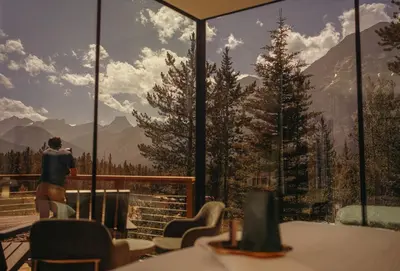 a person standing on a balcony looking out at the mountains at Skyridge Glamping in Kananaskis Village
