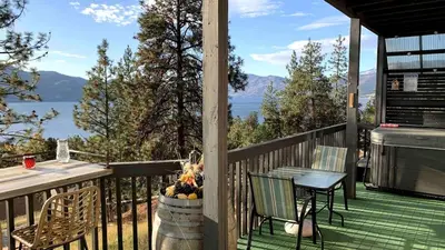 a porch with a table and chairs and a view of the water at Desert Pines Holiday Getaway in Peachland