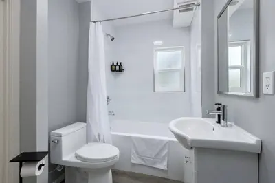 a white bathroom with a toilet and a sink at Spacious 4BR Retreat near YVR and DT in Vancouver