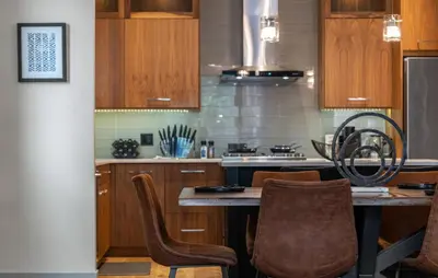 a kitchen with wooden cabinets and a table with chairs at Rare Find, Double King Beds, Cozy and Vibrant in Calgary