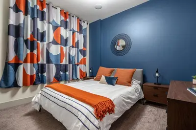 a bedroom with blue walls and a bed with an orange blanket at Rare Find, Double King Beds, Cozy and Vibrant in Calgary