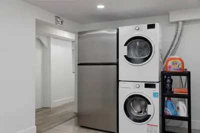a laundry room with a refrigerator and a washer and dryer at Cozy BSMT suite Near UBC, Kits, and DT Vancouver in Vancouver
