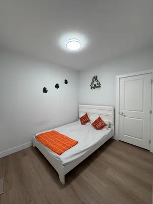 a white bedroom with a bed with an orange blanket at Sweet home 2 bedroom suite in Surrey