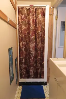 a shower curtain in a bathroom with a blue rug at Friendly Footprint in Golden