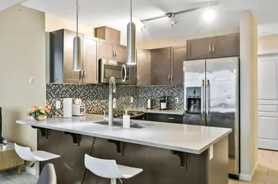 a kitchen with a large island with white counter tops at The Urban Peak on the 19th Floor of the Alura in Calgary