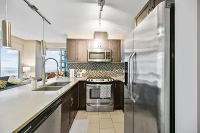 a kitchen with a stainless steel refrigerator and a sink at The Urban Peak on the 19th Floor of the Alura in Calgary