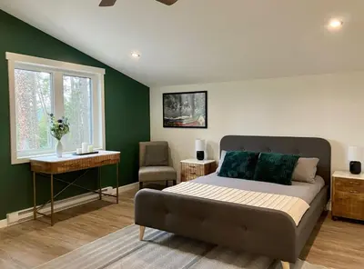 a bedroom with a bed and a table and a window at Valley Edge Lodge in Golden