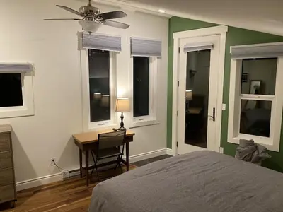 a bedroom with a bed and a desk and windows at Bluebird Nest in Golden