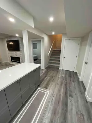 an empty living room with a kitchen and a staircase at HansBnB near Airport in Calgary