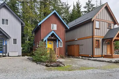 a red barn with a garage and a house at Tyee Retreat Cozy Lofted 1 Bedroom Cabin in Ucluelet