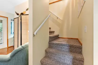 a staircase in a house with a blue couch at Tyee Retreat Cozy Lofted 1 Bedroom Cabin in Ucluelet