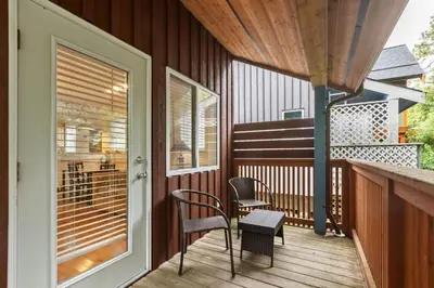 a porch with chairs and a table on a deck at Tyee Retreat Cozy Lofted 1 Bedroom Cabin in Ucluelet