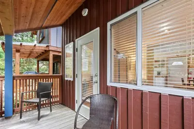 a porch with two chairs and a table and a window at Tyee Retreat Cozy Lofted 1 Bedroom Cabin in Ucluelet