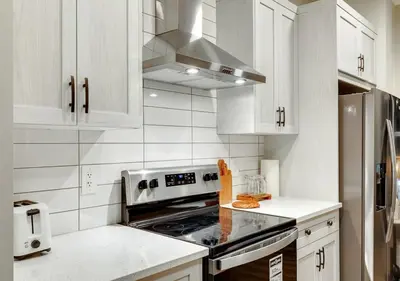 a kitchen with white cabinets and a stove top oven at Neutral Living 6Beds 4Bedrooms and Bonus Room Free Parking in Calgary