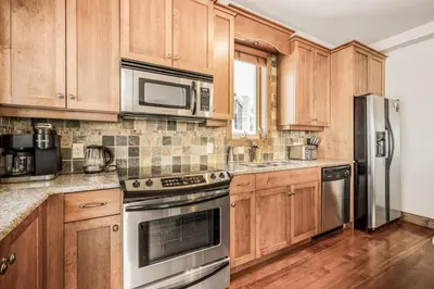 a kitchen with wooden cabinets and stainless steel appliances at Southpoint 25 Two Bdrm Ski In Out w Hot Tub in Big White