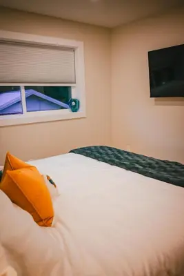 a bedroom with a bed with an orange pillow and a window at Courtenay Luxe Suite in Courtenay