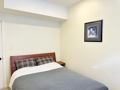 a bedroom with a bed and a picture on the wall at Cozy Guest Suite Near University of Alberta, Southgate Mall, and Downtown in Edmonton