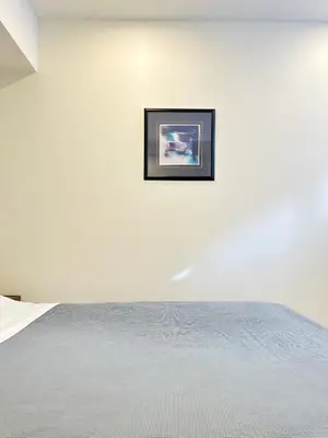 a white bedroom with a picture on the wall at Cozy Guest Suite Near University of Alberta, Southgate Mall, and Downtown in Edmonton