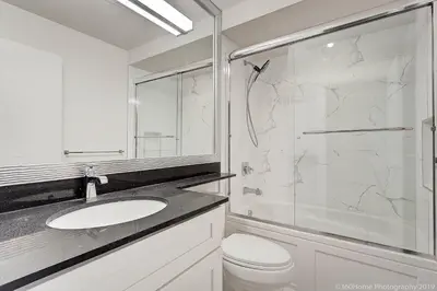 a white bathroom with a sink and a shower at D Peaceful Suite in West Vancouver