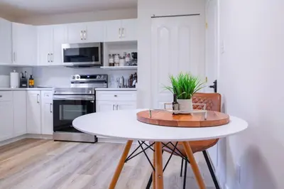 a white kitchen with a table and a potted plant at The Vida 1 Bed Pet-Friendly in Abbotsford