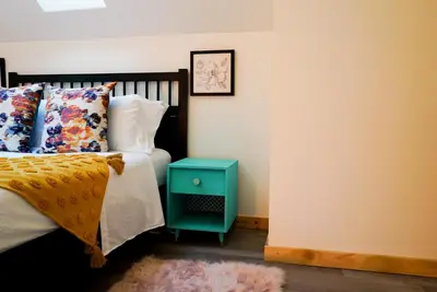 a bedroom with a bed with a blue nightstand next to it at Quirky Farm Stay at Flower Beds Farm - Hot Tub in Qualicum Beach