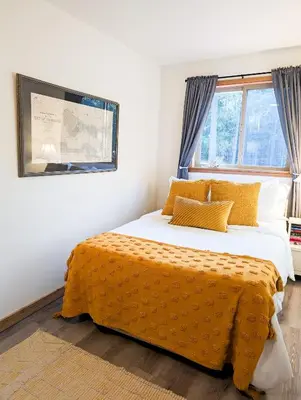 a bedroom with a bed with an orange blanket at Quirky Farm Stay at Flower Beds Farm - Hot Tub in Qualicum Beach