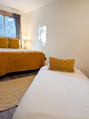 a bedroom with two beds and a yellow couch at Quirky Farm Stay at Flower Beds Farm - Hot Tub in Qualicum Beach