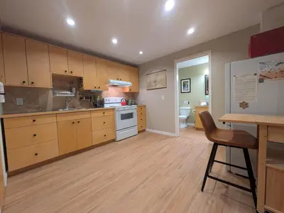 a large kitchen with wooden cabinets and a table at Fresh Studio Apartment in Central Rossland in Rossland