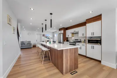 a kitchen with white cabinets and a bar with stools at Your Pleasant stay in 3 bedroom House in Saddle-Ridge in Calgary