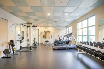 a gym with several treadmills and weights in a room at Yaletown Gorgeous Unit Steps from the Beach in Vancouver