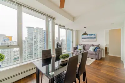 a living room with a table and chairs and windows at Home in the Sky with Gorgeous Water Views in Vancouver