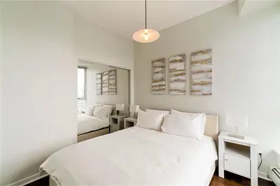 a white bedroom with a bed and a couch at Home in the Sky with Gorgeous Water Views in Vancouver