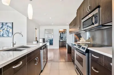 a kitchen with wooden cabinets and stainless steel appliances at Urban Oasis - 2BR Condo Downtown Large Balcony in Calgary