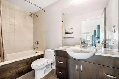 a bathroom with a sink and a toilet and a tub at Urban Oasis - 2BR Condo Downtown Large Balcony in Calgary